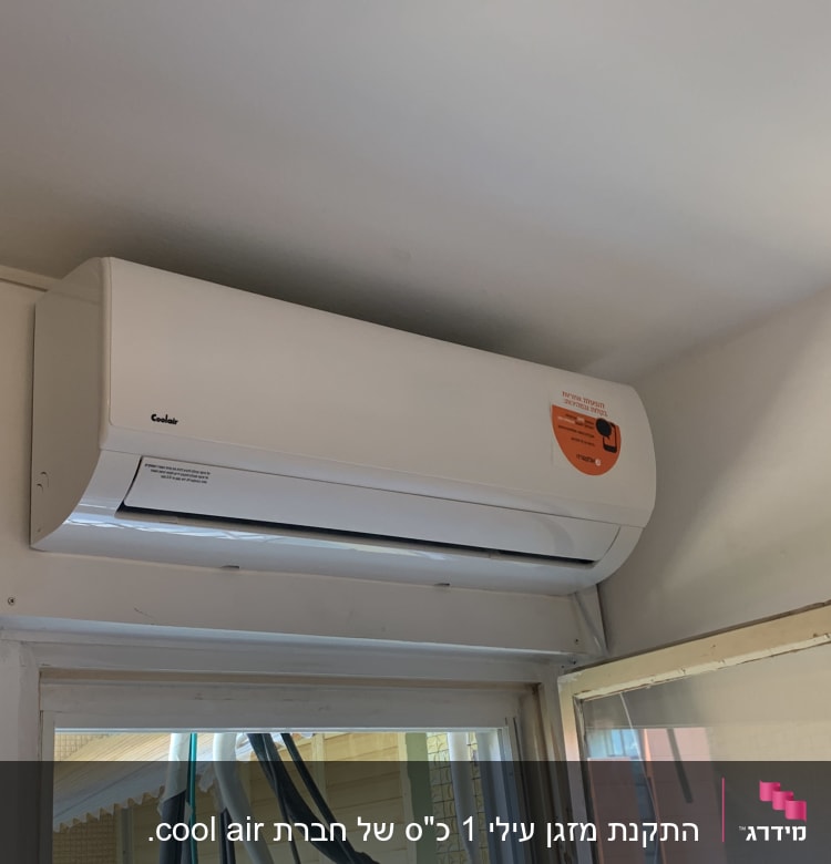 מזגן לבן מותקן על קיר מעל חלון